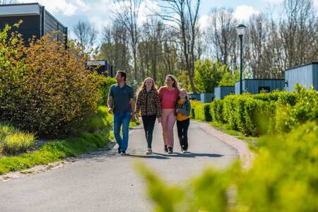 Gezin wandelt tussen vakantiehuizen op vakantiepark EuroParcs Spaarnwoude