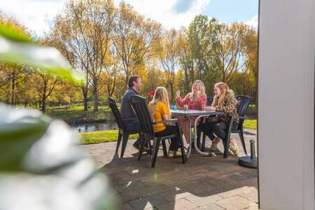 Gezin aan tafel in de tuin van een vakantiehuis op vakantiepark EuroParcs Spaarnwoude