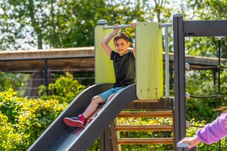 Jongen op de glijbaan in een speeltuin op vakantiepark EuroParcs Veluwemeer