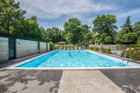 Mensen aan het zwemmen in het buitenbad van Bungalowpark Het Verscholen Dorp