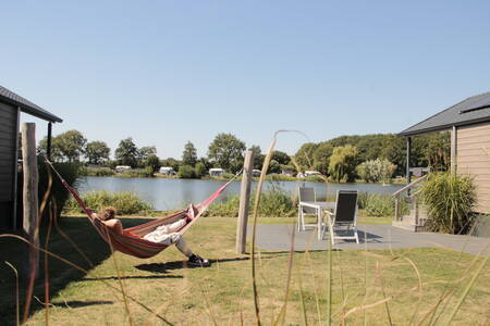 Man in een hangmat in de tuin van een lodge aan het water op Krieghuusbelten