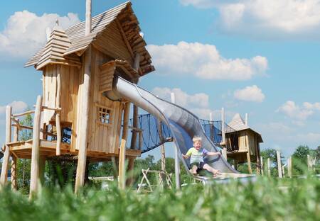 Kind op een glijbaan in een speeltuin op vakantiepark Krieghuusbelten