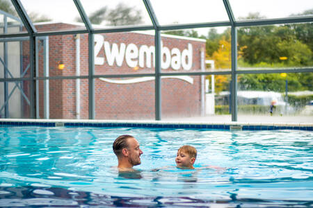 Vader met kind aan het zwemmen in het binnenbad van Krieghuusbelten