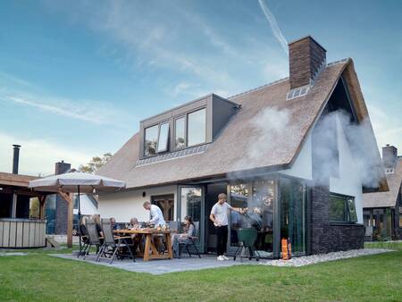 Gezin barbecuet in de tuin van een vakantievilla op vakantiepark Landal Berger Duinen