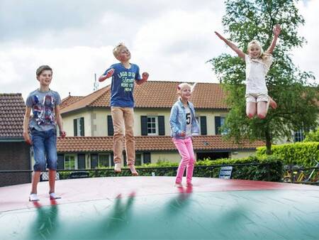 Kinderen springen op de airtrampoline in een speeltuin op vakantiepark Landal Duc de Brabant