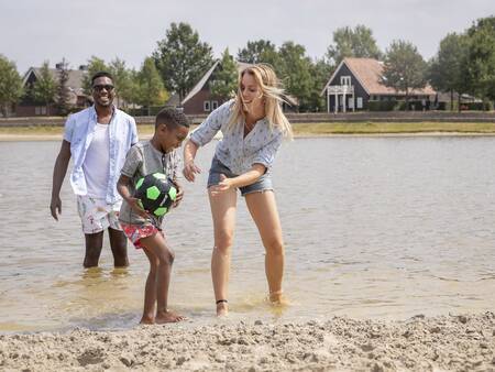 Gezin speelt in het water van het recreatiemeer op vakantiepark Landal Hof van Saksen