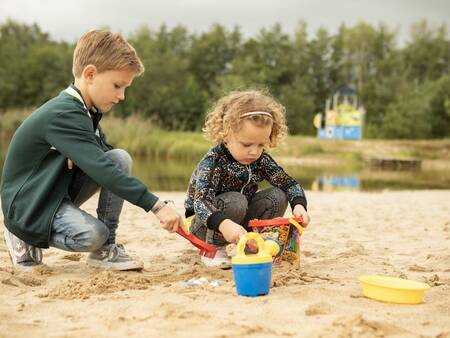 Kinderen spelen op het strand van de recreatieplas van vakantiepark Landal Hunerwold State