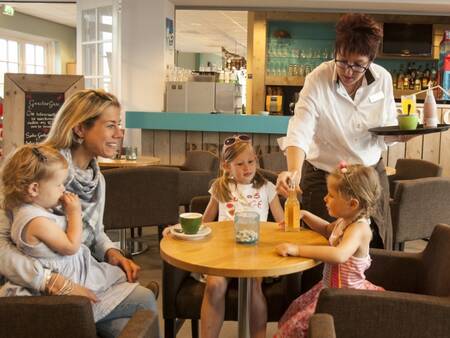 Een gezin geniet van een drankje bij Restaurant De Smokkelaar op Landal Strand Resort Nieuwvliet-Bad