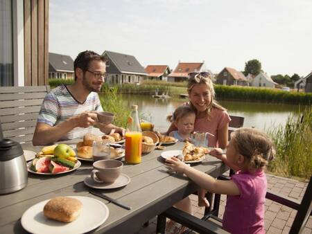 Een gezin eet in de tuin op vakantiepark Landal Strand Resort Nieuwvliet-Bad