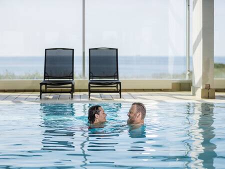Een man en vrouw zwemmen in het zwembad van Landal Strandappartementen Fyrklit