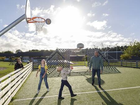 Gezin speelt een potje basketbal op het speelveld van Landal Vakantiepark Søhøjlandet