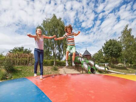 Kinderen springen op de airtrampoline in de speeltuin op vakantiepark Landal Warsberg