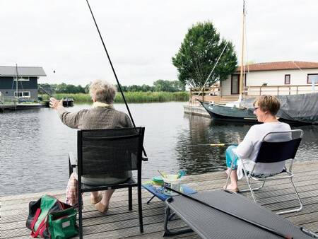 Man vist vanaf de steiger bij zijn vakantiehuis op vakantiepark Landal Waterpark Sneekermeer