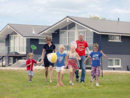 Gezin wandelt op een grasveld voor vakantiehuizen op Landal Waterpark Sneekermeer