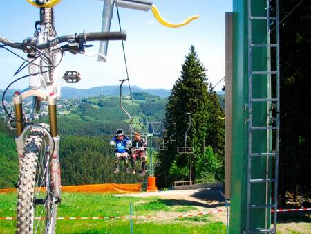 Landal Winterberg - 2 mensen en een mountainbike in een stoeltjeslift