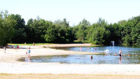 Kinderen op het strand en in het water van het recreatiemeer op vakantiepark Molecaten het Landschap