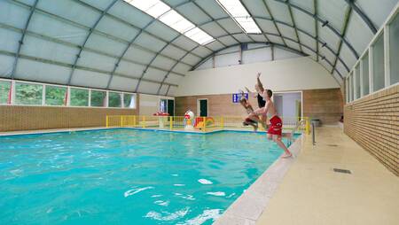 Kinderen springen in het binnenbad van vakantiepark Molecaten het Landschap