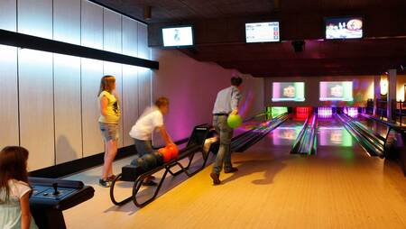 Gezin aan het bowlen op de bowlingbaan van vakantiepark Molecaten Park De Koerberg
