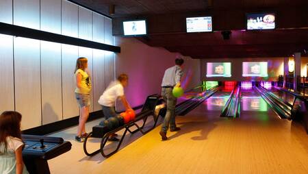 Gezin aan het bowlen op de bowlingbaan van vakantiepark Molecaten Park De Koerberg