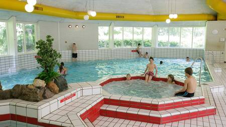 Mensen zwemmen in het binnenbad met bubbelbad van vakantiepark Molecaten Park De Leemkule