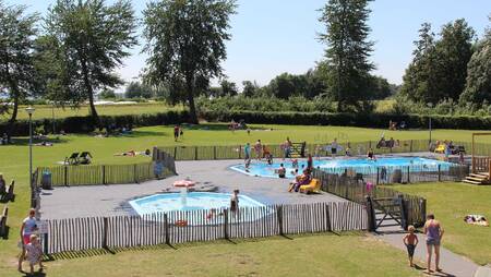 Mensen in het buitenbad met ligweide op vakantiepark Molecaten Park Flevostrand