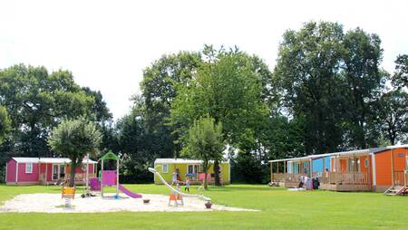 Chalets op een veld met een speeltuin op vakantiepark Molecaten Park Kuierpad