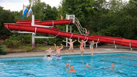 Mensen aan het zwemmen in het buitenbad met glijbaan op vakantiepark Molecaten Park Kuierpad