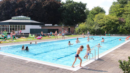 Mensen aan het zwemmen in het buitenbad van vakantiepark Molecaten Park Landgoed Ginkelduin