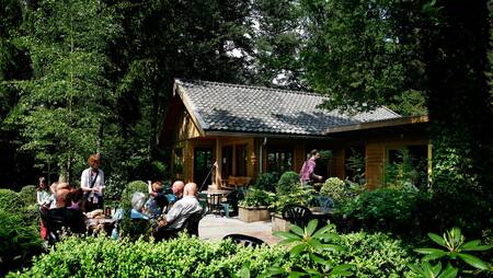 Mensen zitten op het terras van de kantine van vakantiepark Molecaten Park Landgoed Molecaten