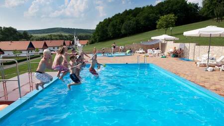 Kinderen springen in het buitenbad van vakantiepark Molecaten Park Legénd Estate