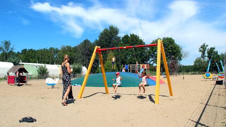 Kinderen op een schommel in een speeltuin op vakantiepark Molecaten Park Rondeweibos