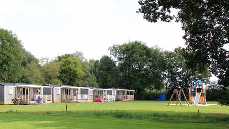 Chalets van het type "Pioen" op een veldje met een speeltuin op vakantiepark Molecaten Park ’t Hout