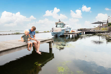 Vader en zoon aan het vissen op een steiger op vakantiepark Oesterdam Resort