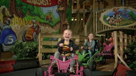 Kinderen op go-carts in binnenspeeltuin "Kids Valley" op vakantiepark Park Molenheide