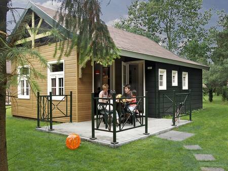 Mensen in de tuin van bungalow type "Relaxis" op vakantiepark Park Molenheide