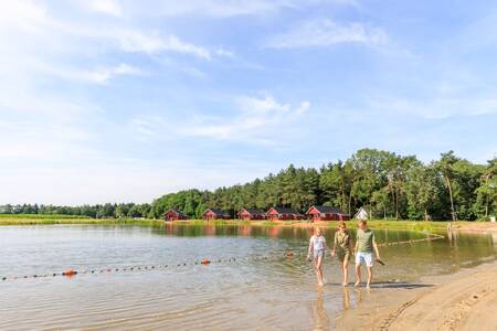 Gezin wandelt door het water van het meer op vakantiepark RCN de Flaasbloem