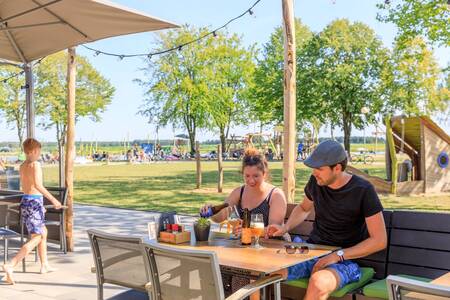 Stel eet op het terras van Brasserie 't Smokkelstrand op vakantiepark RCN de Flaasbloem