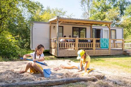 Kinderen spelen in een zandbak bij een chalet op vakantiepark RCN De Noordster