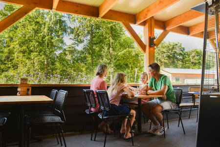 Gezin aan het eten op het overdekte terras van het restaurant op vakantiepark RCN De Noordster
