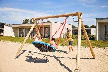 kinderen op een schommel in een speeltuin op vakantiepark RCN de Schotsman