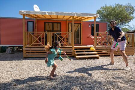 Vader en dochter tennissen voor een chalet op vakantiepark RCN Domaine de la Noguière