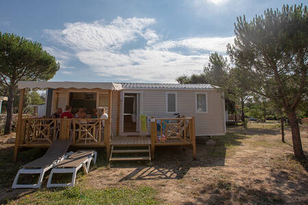 Gezin op de veranda van een mobil home type Monaco op vakantiepark RCN Domaine de la Noguière