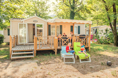 Gezin in de tuin van een mobil home op vakantiepark RCN La Bastide en Ardèche