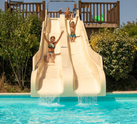 Kinderen glijden van de glijbanen in het buitenbad van vakantiepark RCN la Ferme du Latois