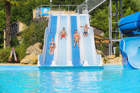 Kinderen glijden van een brede glijbaan in het buitenbad van vakantiepark RCN Le Moulin de la Pique