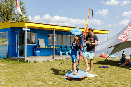 Kind op een surfplank bij de surfschool op vakantiepark RCN Zeewolde