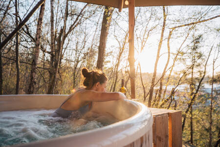 Vrouw in een hottub in een boomhut op Recreatiedomein Warredal