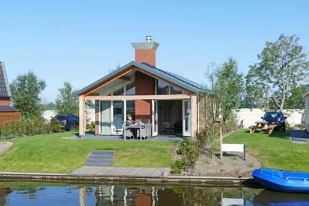 Een loungeset in de tuin van een vakantiehuis aan het water op Recreatiepark Tusken de Marren