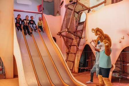 Kinderen op een glijbaan in de binnenspeeltuin van vakantiepark Roompot Beach Resort Nieuwvliet-Bad