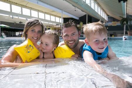 Een gezin is aan het zwemmen in het binnenbad van vakantiepark Roompot Beach Resort